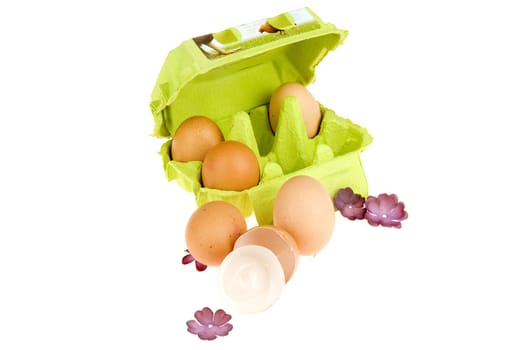 three eggs in a green box, two in front of the box and egg shells
