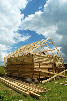 Building of a bathhouse from a bar on a country site against the sky with clouds