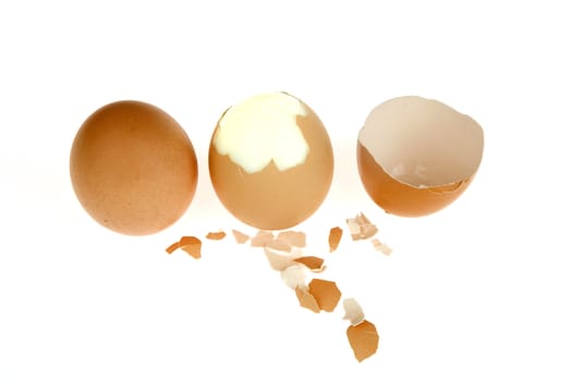 three eggs in a row, a whole one, a peeled one and the shells