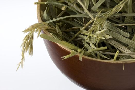 a handful of grass hay in a round wooden bowl on white background, copy space