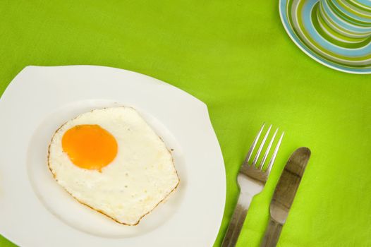 a fried egg on a plate with a fork and a knife