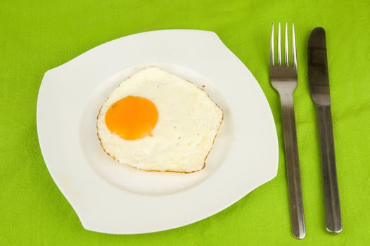 a fried egg on a plate with a fork and a knife