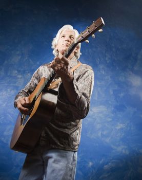 Guitarist with his Instrument in front of a Blue Wall