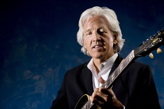 Guitarist with his Instrument in front of a Blue Wall
