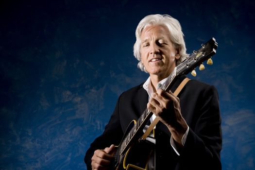Guitarist with his Instrument in front of a Blue Wall