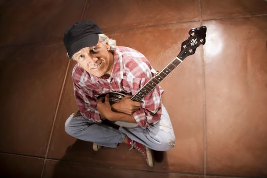 Banjo Player Sitting Indoors on Cement Floor