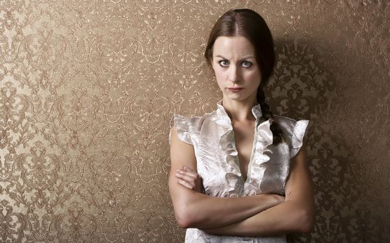 Pretty young woman waiting leaning up against a wall with gold wallpaper