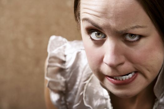 Young woman making stern face in front of a gold wallpaper background