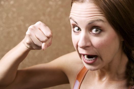 Angry Young Woman in Front of Gold wallpaper Throwing a Punch