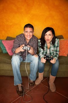 Attractive Hispanic Couple Playing a Video Game with Handheld Controllers