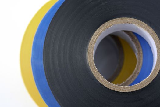 Electrical insulation tape stacked in three colours black, blue and yellow