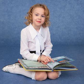 Schoolgirl reading children's book sitting on the floor
