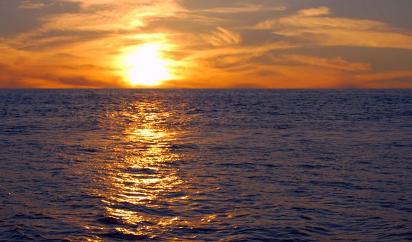 ocean's sunset with gold sunbeam over water