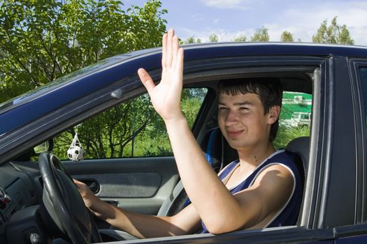 A young man smiling as he sits in a blue car