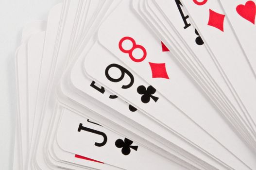 Close up capturing a small portion of a deck of playing cards spread on a white surface.