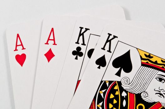 Close up on the top halves of two ace and two king playing cards overlaying one another on a white surface.