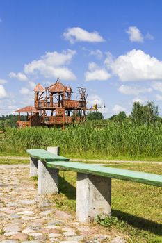 Wooden bench at the park in Lithuania village. In the second plan a celebrity of park - the "house of monkeys"