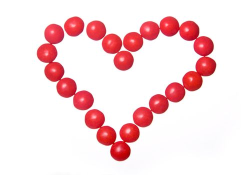 Red candies in a heart shape against white