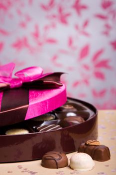 Luxury chocolates in a box with pink satin lid, shallow depth of field with focus on chocolates at front