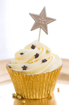 Cupcake decorated with gold dragees and chocolate stars