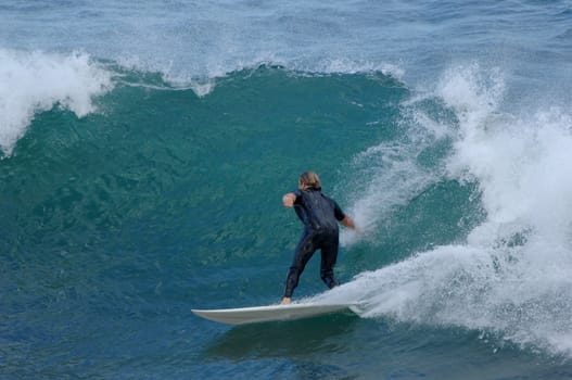 A male surfer takes off down a wave