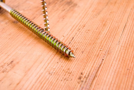 Two screws on wooden background