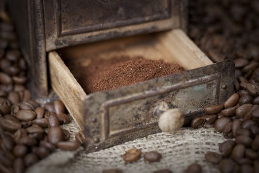 Antique coffee grinder filled with coffee beans - selective focus on ground coffee