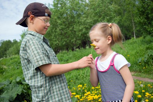 Young boy giving a young girl of dandelion