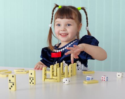 Cheerful child playing with small toys, sitting at the table