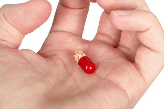 Mysterious little multi-colored pill in the palm