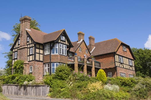 A large detached tudor style house with a blue sky