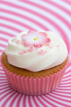 Pink cupcake decorated with a flower and pink sugar