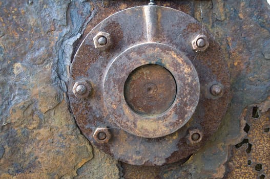 A peice of rusty metal with a round piece bolted to it