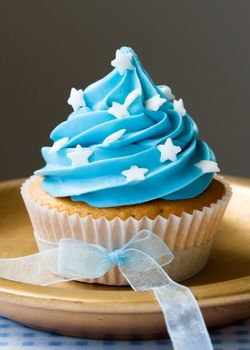 Single blue cupcake decorated with stars and an organza ribbon