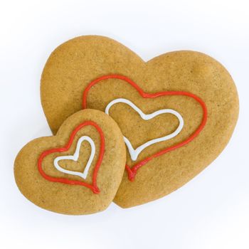Two heart shaped gingerbread cookies decorated with icing