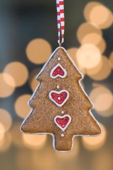 Christmas tree ornament hangs in front of de-focused christmas lights