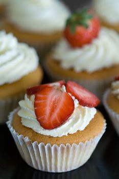 Cupcakes decorated with whipped cream and fresh strawberries