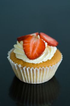 Cupcake decorated with strawberries and a swirl of cream