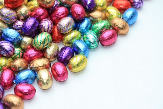 A pile of colored easter chocolate eggs with copy space