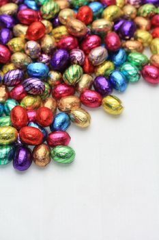 A pile of colored easter chocolate eggs with copy space