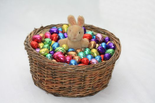 An easter bunny and chocolate eggs in a wicker basket