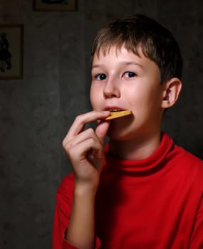 The little boy chews a cracker