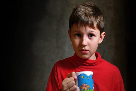 The little boy drinking a tea from color cup
