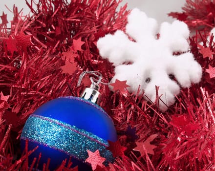 Christmas ornaments  blue ball and snowflake on red tinsel backrownd