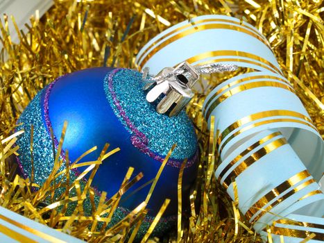 Christmas blue ornaments and colorfull  ribbon on background of gold tinselbackground