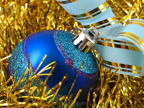 Christmas blue ornaments and colorfull  ribbon on background of gold tinselbackground