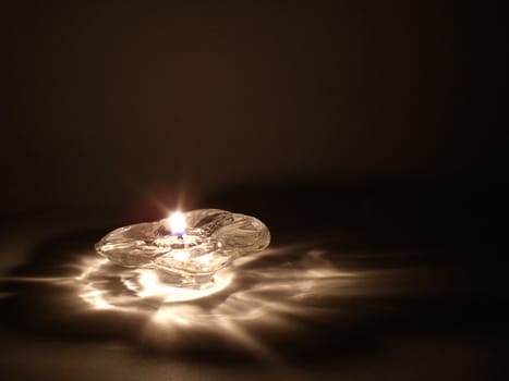 Single flame on a flower candle glowing in the night