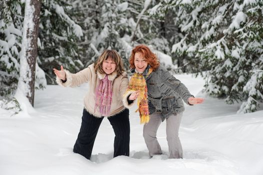 Couple of attractive friends having fun on winters day in forest.