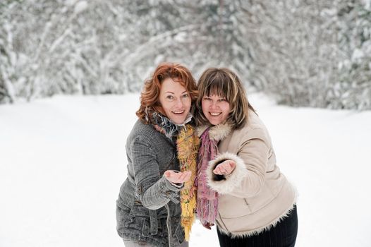 Couple of attractive friends having fun on winters day in forest.