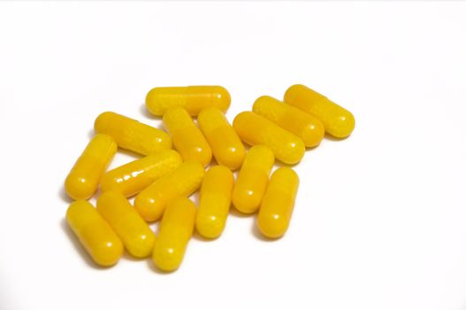 close up on stack of yellow capsules, isolated on white